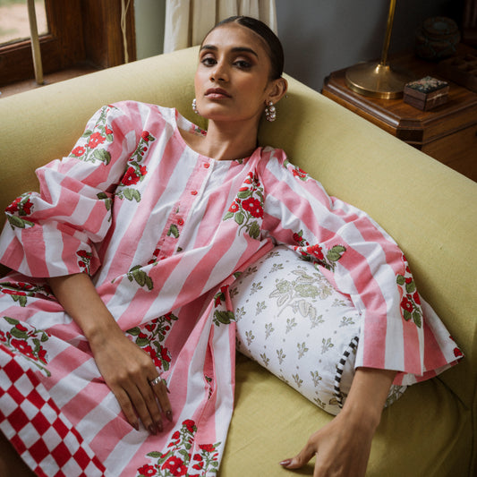 Woman in a pink and white floral dress sitting on a yellow couch.
