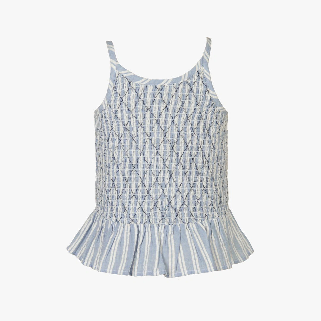 A sleeveless baby top with a smocked bodice and ruffled hem, featuring a light blue and white monogram pattern and vertical stripes on the skirt, shown against a plain white background.