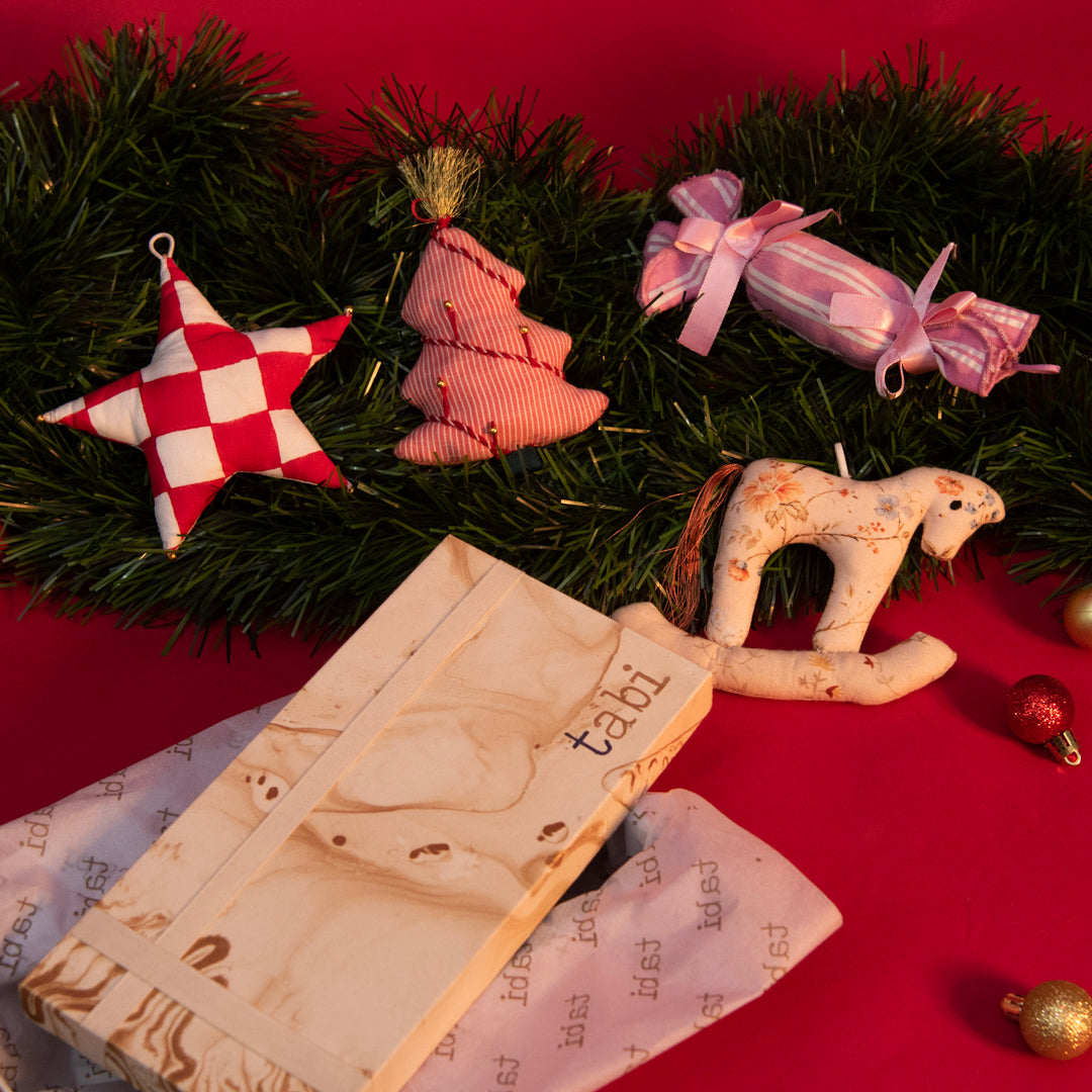 Decorative Christmas ornaments on a red surface with a book titled 'tabi'.