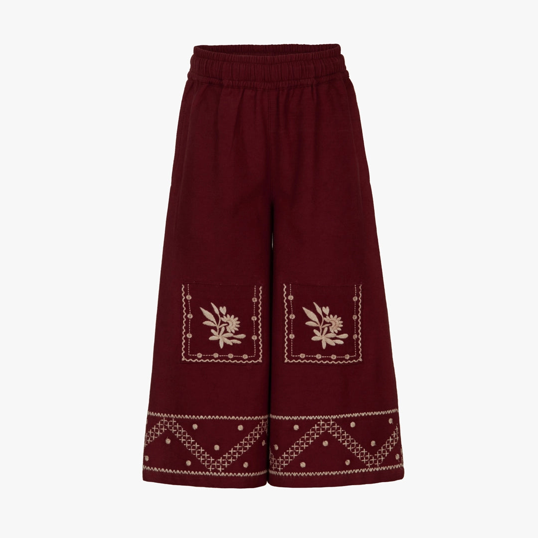 Maroon pants with white embroidery on a light gray background