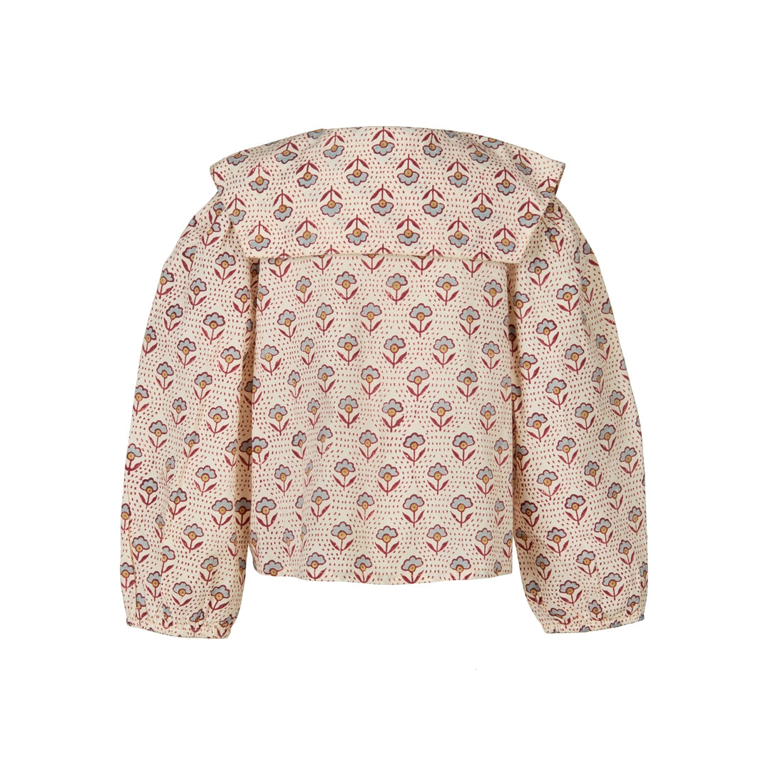 A cropped jacket with a high ruffled collar and long sleeves, featuring an all-over repeating floral and geometric print in muted red, blue-gray, and brown on a warm beige background.