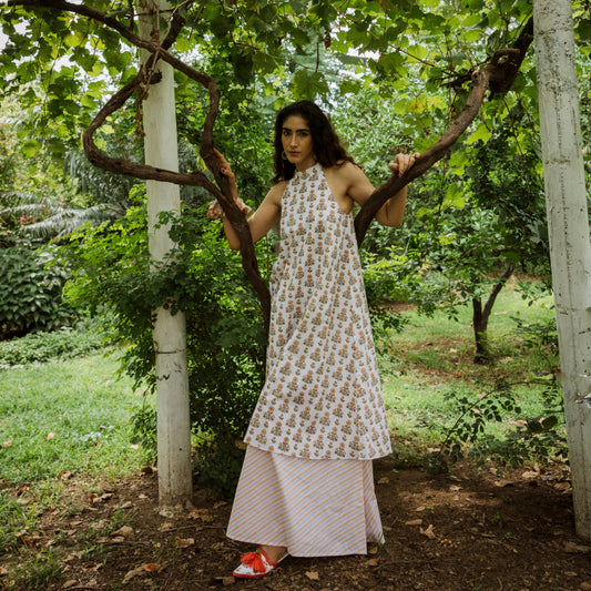 Woman in a floral dress standing under a tree in a garden