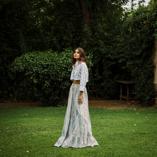 Woman in a patterned outfit standing in a garden with greenery