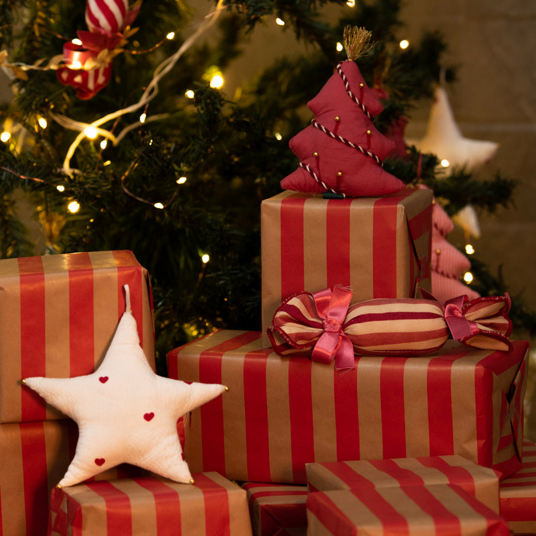 Red and gold striped presents with decorative items against a Christmas tree background