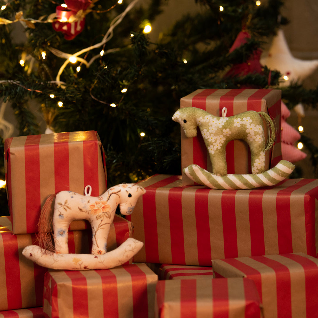 Decorative rocking horses on striped presents with a Christmas tree in the background
