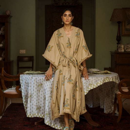Woman in a floral dress standing in a room with a table and chairs.