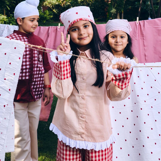 Children in traditional attire standing behind a line of clothes with polka dot patterns.