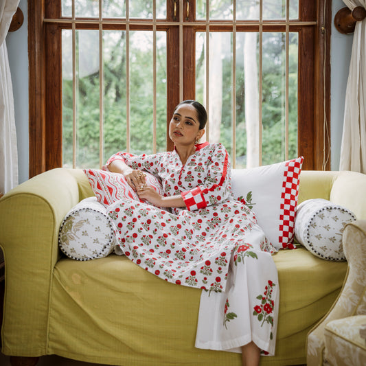 Woman in a floral robe sitting on a yellow couch with decorative pillows.