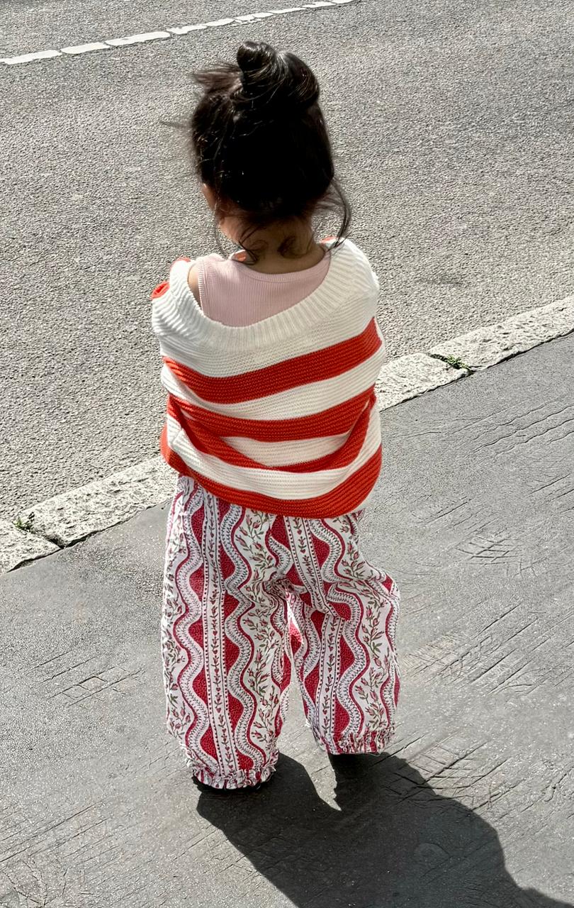 Child wrapped in a red and white striped blanket on a street