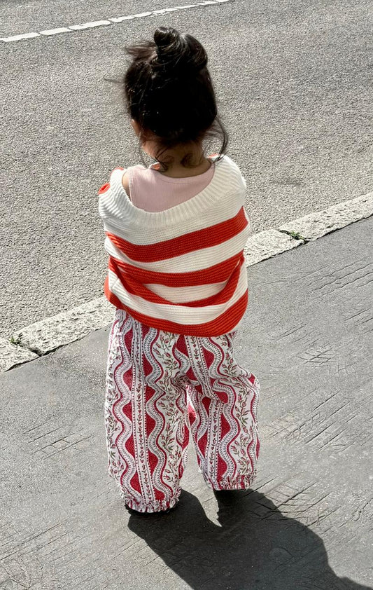 Child wrapped in a red and white striped blanket on a street