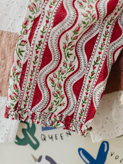 Close-up of a red and white embroidered fabric with floral patterns on a textured surface.