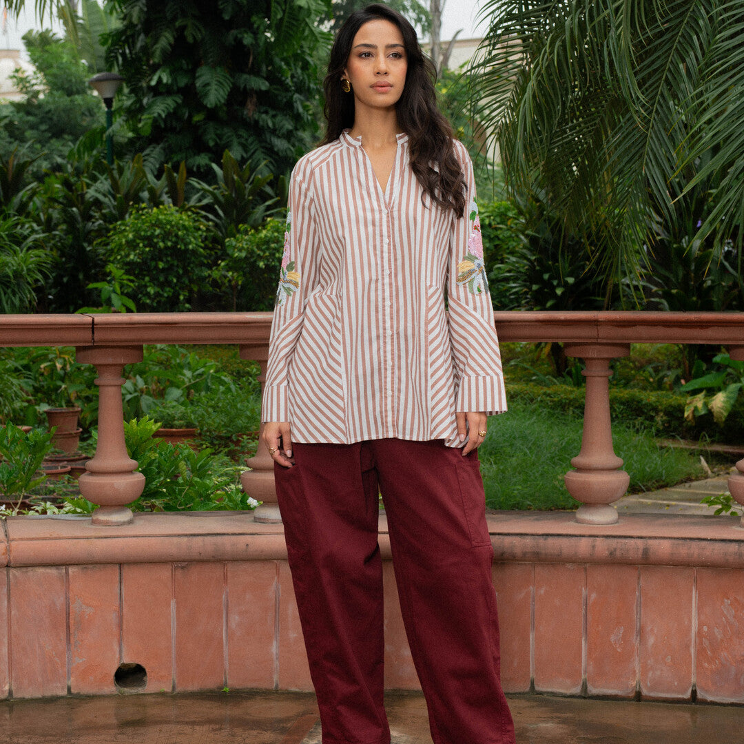 women is wearing hand-embroidered stripes top and maroon denim.
