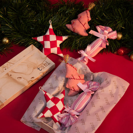 Decorative Christmas ornaments on a red surface with a 'tabi' box.