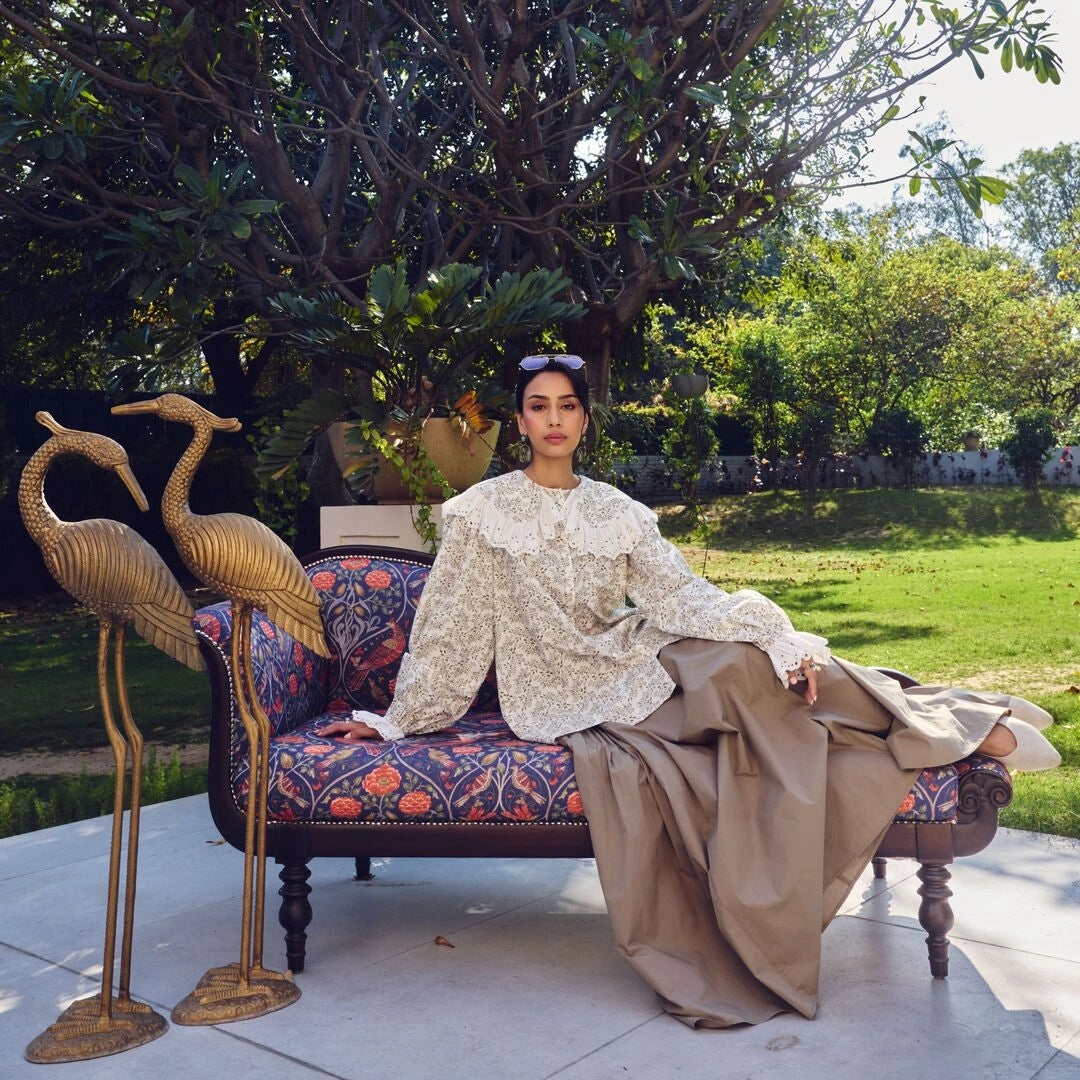 Woman sitting on a decorative chair outdoors with ornate cranes nearby