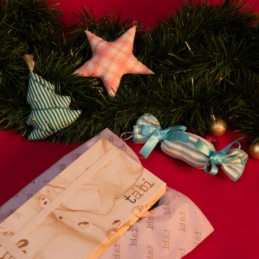 Decorative Christmas wreath with star ornament, candy, and wooden card on a red surface.