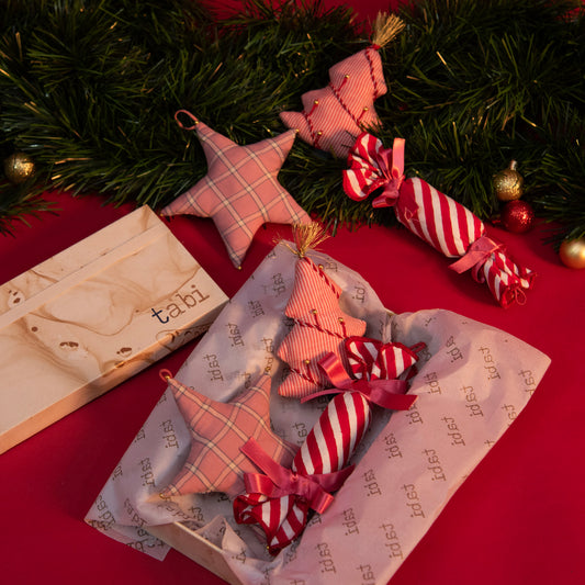 Christmas-themed hair accessories on a red surface with greenery and a box.