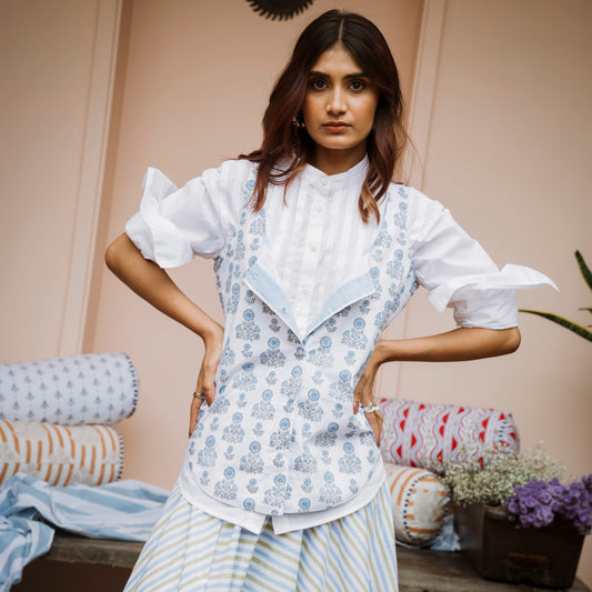 Woman wearing a white blouse with floral patterns and striped pants in a casual setting.