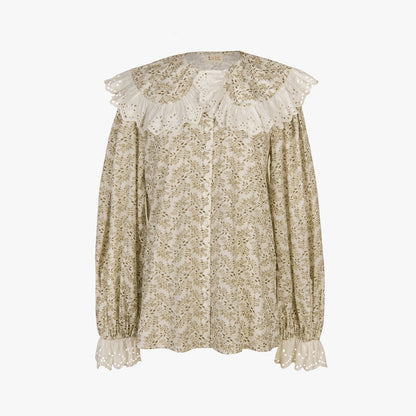 A long-sleeve blouse with a beige and white floral pattern, featuring a large ruffled eyelet collar and matching ruffled cuffs, shown against a plain white background.