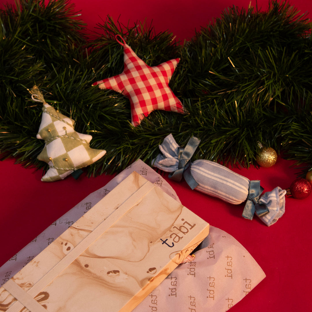 Christmas decorations including a star ornament, cracker, and tree on a red background.
