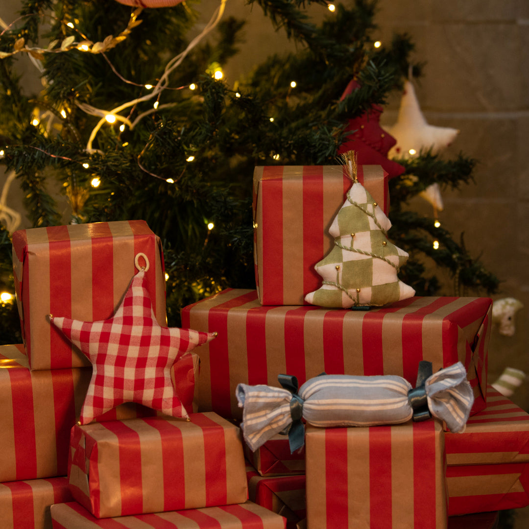 Red and brown striped presents with decorative items in front of a Christmas tree.