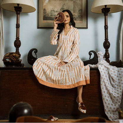 A woman wearing a long-sleeved kurta dress with  orange stripes 