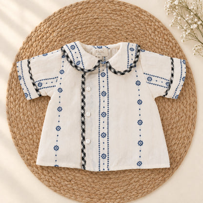 A baby clothing set  featuring a short-sleeve cream shirt with blue embroidered patterns 